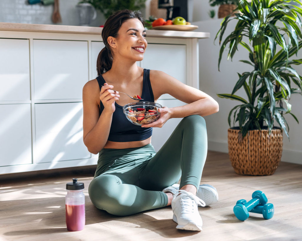 Młoda kobieta jedząca wartościowy posiłek po treningu